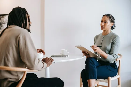 Manager en medewerker hebben een einde proeftijdgesprek aan tafel. Manager neemt notities