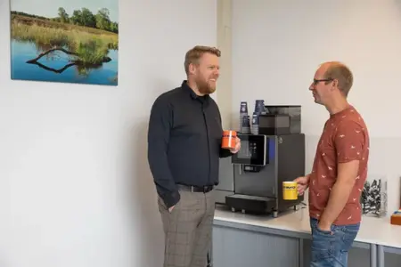 IFS Ultimo medewerkers die bij een koffieapparaat met elkaar zijn aan het praten over Learned platform