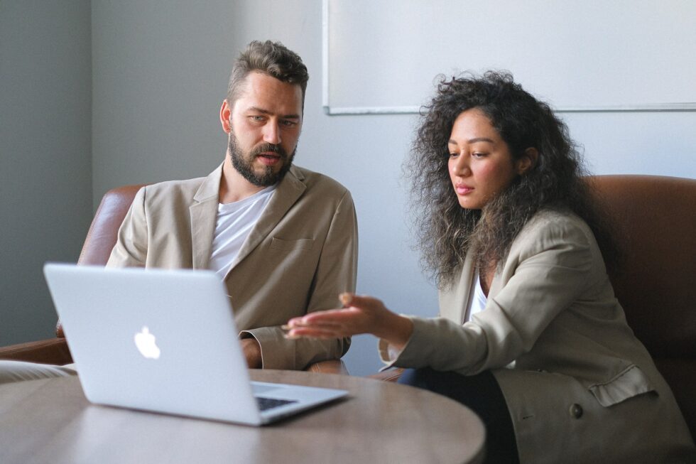 Manager voert een loopbaangesprek met de medewerker. Zij wijst naar de laptopscherm om ontwikkelpunten te bespreken