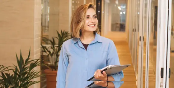 HR manager lachend met een laptop en notitieboekje in handen op weg naar de planningsgesprek