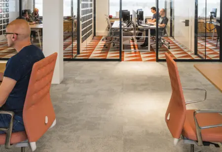 Proxsys kantoor, man zit aan bureau met oranje stoelen