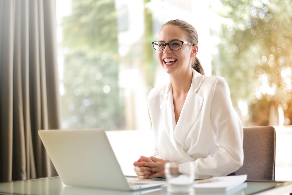 Lachende vrouw aan het werk aan duurzame inzetbaarheid achter laptop