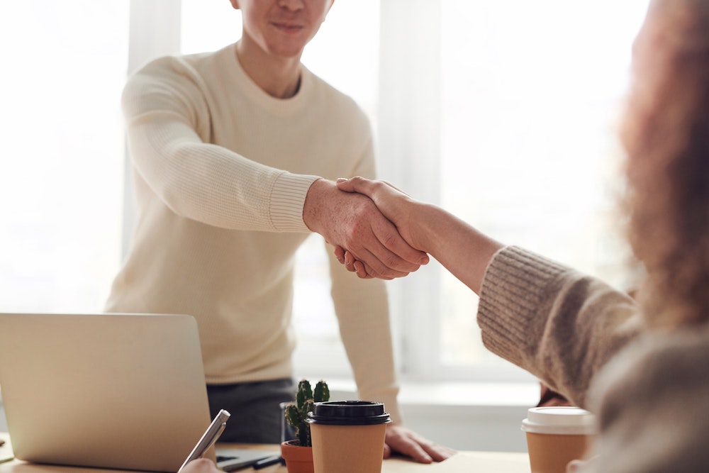 Vrouw komt naar interview en schudt de hand van de interviewer