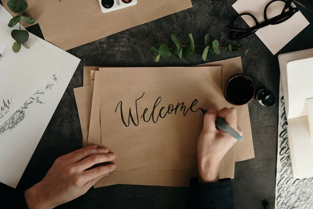 Vrouw schrijf 'welcome' op papier