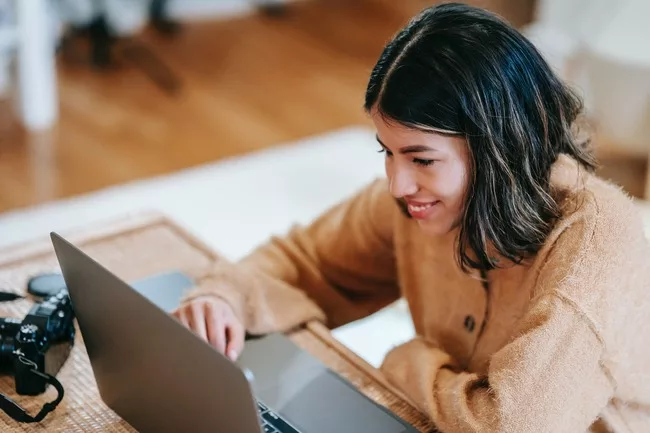 Business Development Representative zit lachend voor haar laptop